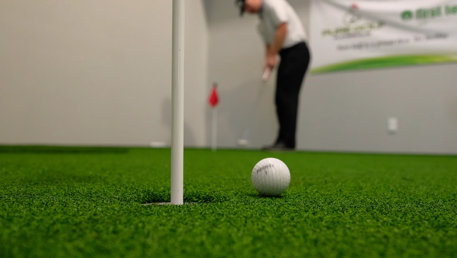 A close up of a golf ball on an indoor practice putting green at Pure Golf